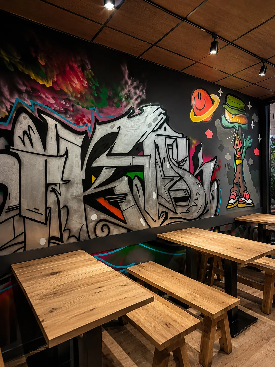 Graffiti-Kunst und Holzbänke im Innenraum von Gökis